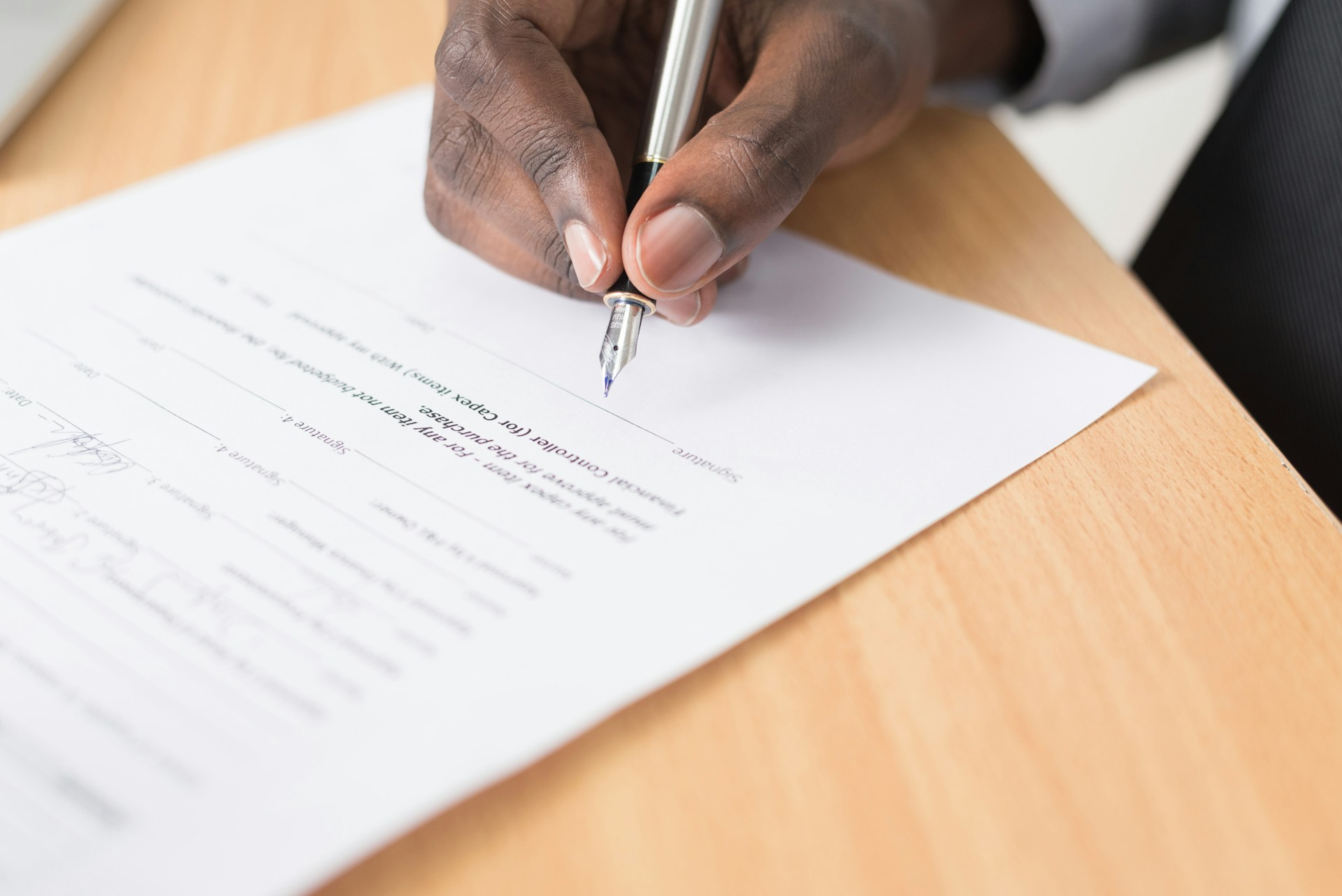 Close-up of a hand signing a contract with a fountain pen, representing commercial contract translation